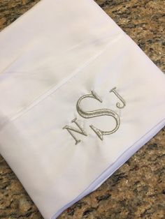 an embroidered monogrammed napkin sits on a granite countertop with the letter s n