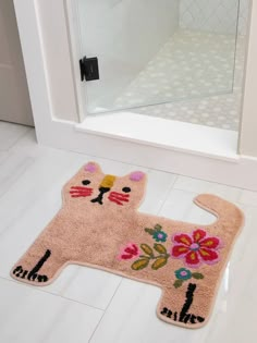 a cat rug on the floor in front of a bathroom door with a glass shower