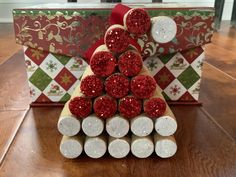 a christmas tree made out of wine corks on top of a wooden table next to a red and white box