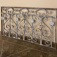 a metal fence sitting on top of a tile floor next to a wall with flowers