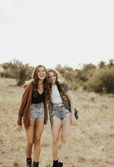 two young women are walking together in the field