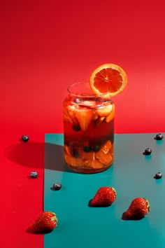 a glass jar filled with fruit sitting on top of a blue and red tablecloth