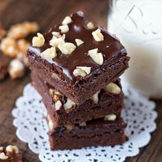 three brownies stacked on top of each other with nuts and milk in the background