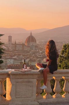 a woman sitting on top of a stone bench with a bottle of wine in her hand