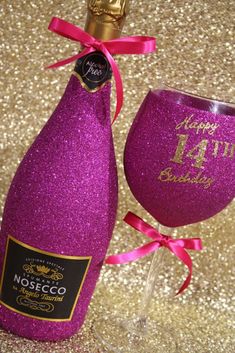 a purple wine bottle with a glass next to it on a gold glitter tablecloth