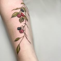 a tattoo with berries and leaves on the arm