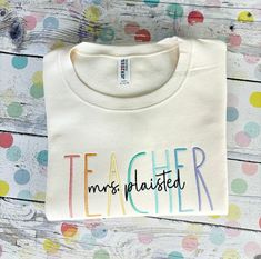 a white t - shirt with the words teacher printed on it and multicolored polka dots