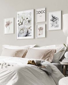 a bed with white sheets and pink pillows in a bedroom next to pictures on the wall