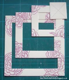 cut out pieces of paper sitting on top of a blue cutting mat with pink and white flowers