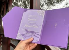 a person holding up a purple wedding card