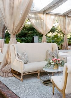 a living room filled with furniture under a white tent covered in drapes and curtains