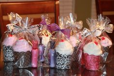 small cupcakes wrapped in clear cellophane and decorated with bows are sitting on a table