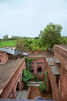 an aerial view of a courtyard with brick buildings and green plants growing on the roof