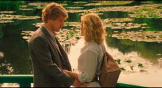 a man and woman standing next to each other on a boat in front of water lillies