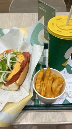 a tray with a hot dog and french fries next to a cup of drink on it