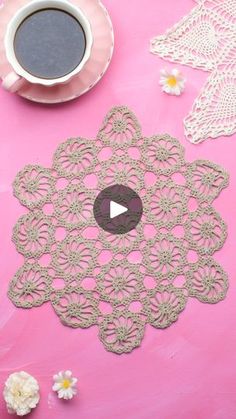 a pink table topped with doily next to a cup of coffee and white flowers