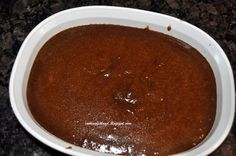 a white bowl filled with brown sauce on top of a counter