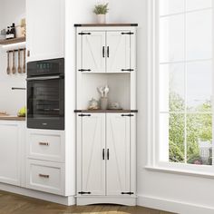 a kitchen with white cabinets and an oven in the corner next to a large window