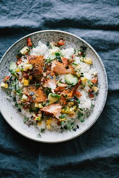 a white plate topped with rice covered in meat and veggies on top of a blue table cloth