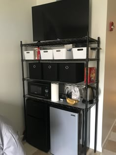 a black shelf with white bins on top of it next to a television and other items