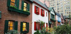 a row of brick buildings with green shutters and red window boxes on the windows