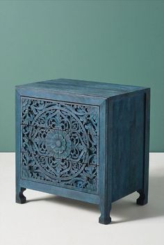 an intricately carved wooden box on a white table with green wall in the background