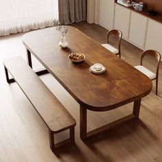 a wooden table with two chairs and a bowl of food on it in front of a window