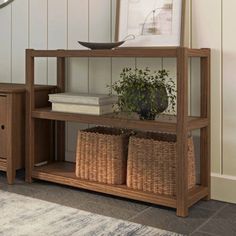 a wooden shelf with baskets on top of it next to a wall mounted art piece