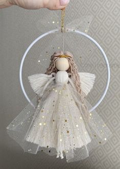 a hand holding an ornament with a white angel on it's side