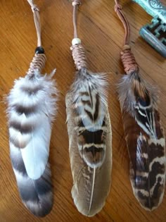 three feathers hanging from strings on a wooden table