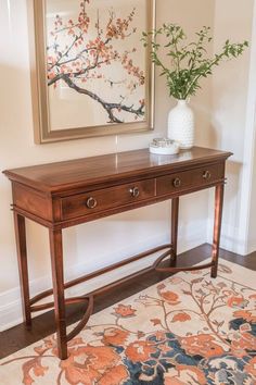 a wooden table sitting in front of a painting on the wall next to a rug