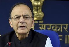 an old man with glasses sitting in front of a microphone and looking at the camera