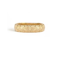 a gold wedding band with small flowers on the inside and outside, set against a white background