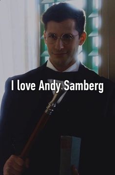 a man in a suit holding a pipe with the words i love andy samberg