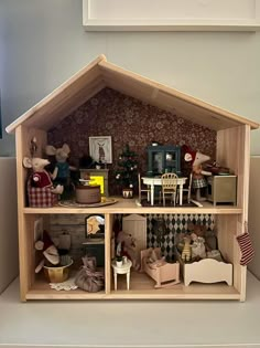 a doll house with furniture and dolls inside it on a table next to a wall