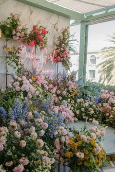 flowers and greenery are arranged in front of a sign that says baby's first birthday