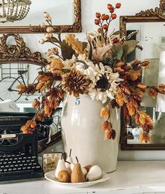 a vase filled with flowers sitting on top of a table next to a typewriter