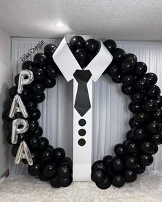 black and white balloons are arranged in the shape of a man's shirt, tie and letters