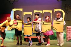 children are standing in front of a school bus with their hands on the back of it