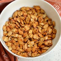 a white bowl filled with pumpkin seeds on top of a table