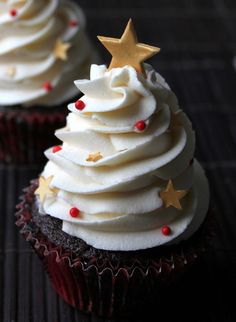 two cupcakes decorated with white frosting and gold stars