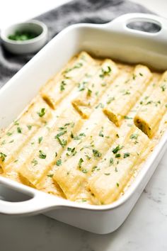 a casserole dish with cheese and parsley in it on a marble table