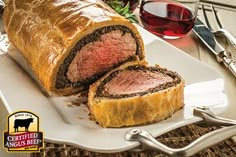 a meatloaf roll cut in half on a plate next to wine glasses and utensils