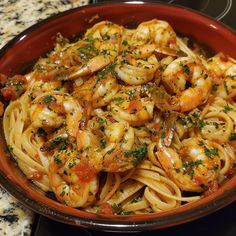 a bowl filled with pasta and shrimp on top of a stove