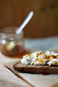 a piece of bread with spread on it sitting on top of a wooden cutting board