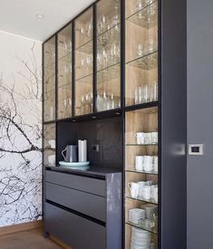 an empty glass cabinet with dishes and cups on it in front of a painted wall