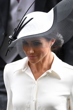 the woman is wearing a white hat with black feathers on it's head and she has a veil over her face