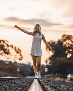 a woman is walking on the railroad tracks with her arms out and she's smiling