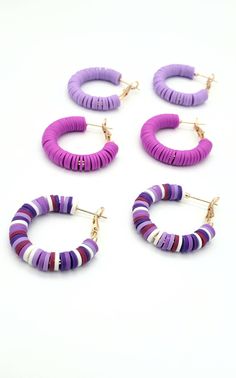 four pairs of hoop earrings in purple, white and pink colors on a white background