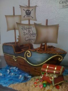 a birthday cake with a pirate ship on it's side and other items in the foreground